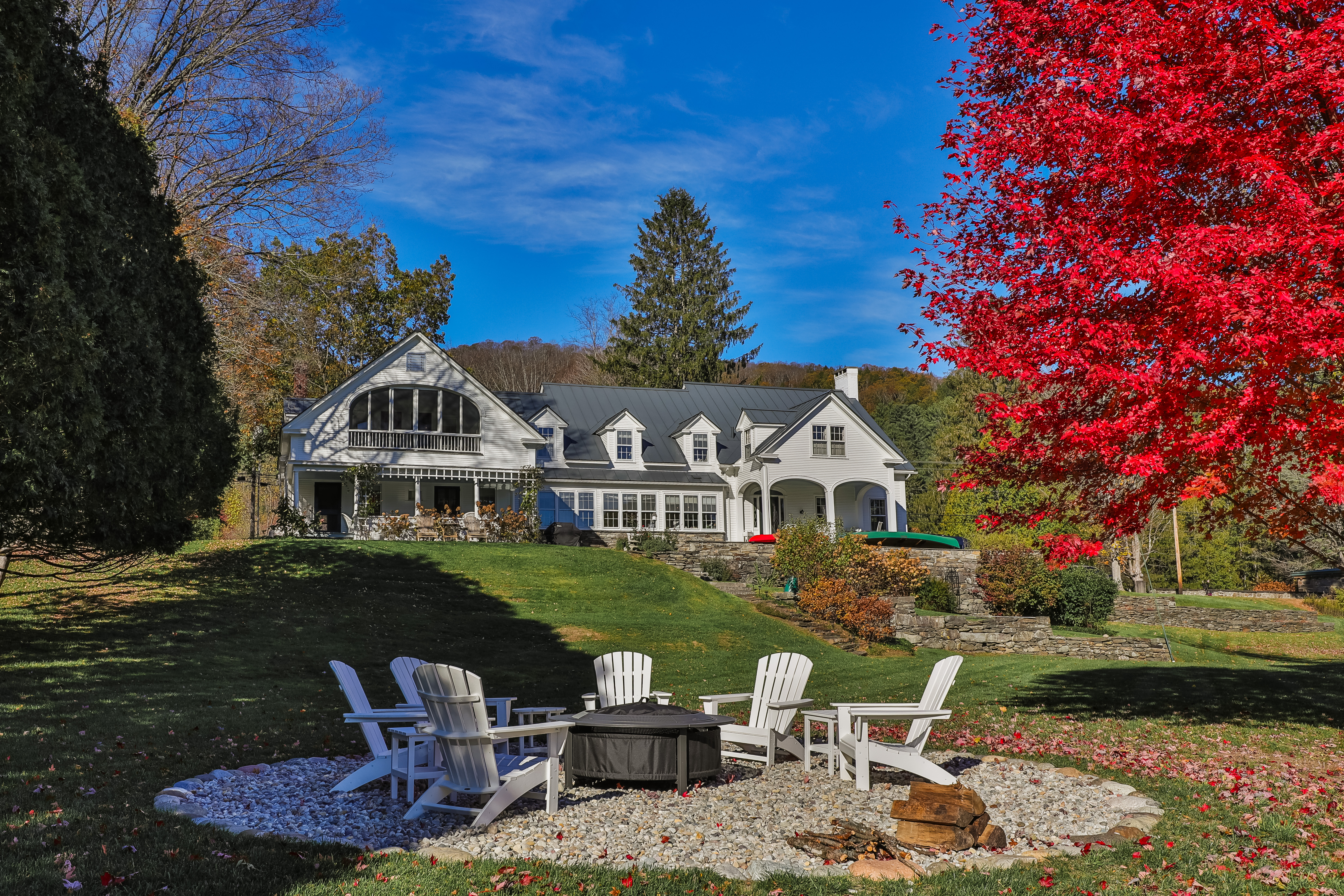Woodstock Village Riverfront Home in autumn with fire pit seating in foreground